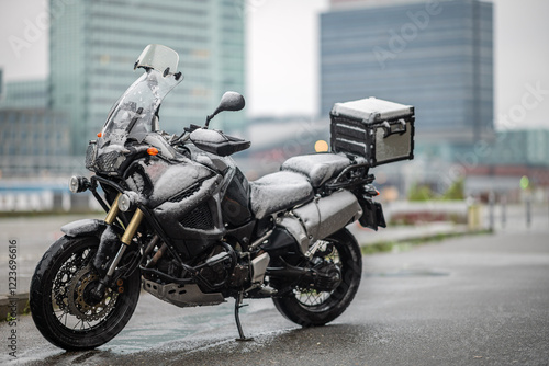 A large black touring motorcycle is covered in snow. The end of the motorcycle season, winter. The inscriptions 