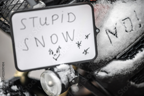 A large black touring motorcycle is covered in snow. The end of the motorcycle season, winter. The inscriptions 