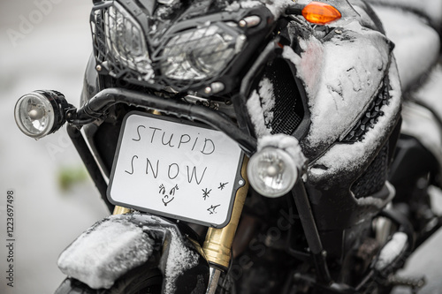 A large black touring motorcycle is covered in snow. The end of the motorcycle season, winter. The inscriptions 
