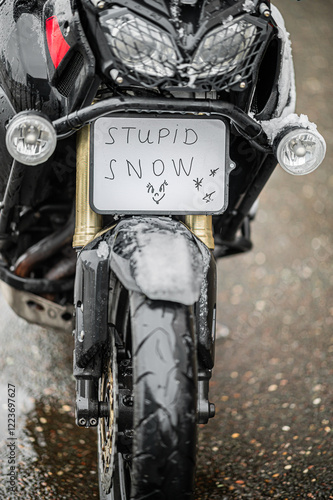 A large black touring motorcycle is covered in snow. The end of the motorcycle season, winter. The inscriptions 