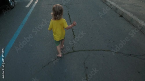 Wallpaper Mural On summer day, cheerful child in yellow t-shirt joyfully walks barefoot on cracked pavement. Toddler exploring outdoors with carefree delight that defines childhood Torontodigital.ca