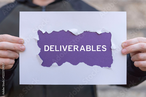 Obraz na płótnie Man holding composition of sheets of paper with text: DELIVERABLES. Concept of business deliverables. Project deliverable. w salonie