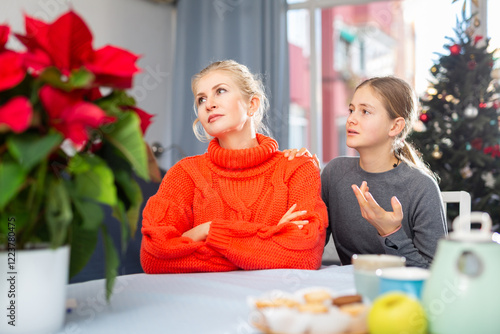 Unhappy mother ignoring her teenage daughter before Christmas, girl trying conversate with her photo