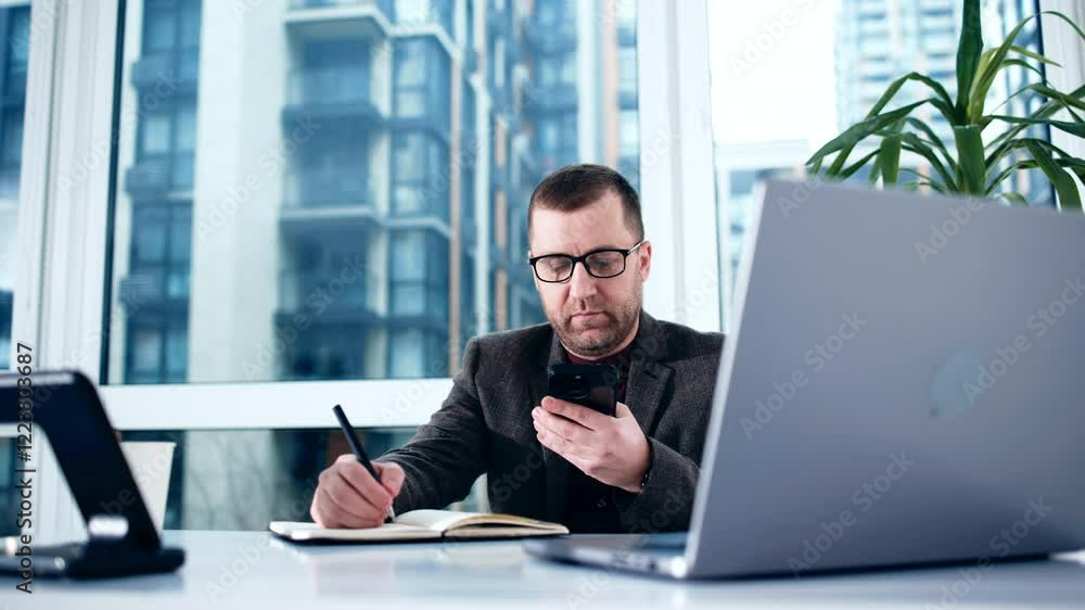 A businessman works on a laptop in a modern office, receiving good news or feeling satisfied with his work. Concept: success, fulfillment, and achievements in professional life. A businessman works on a laptop in a modern office, receiving good news or feeling satisfied with his work. Concept: success, fulfillment, and achievements in professional life.