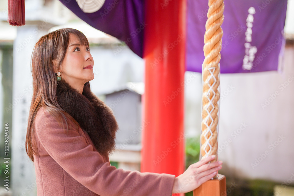 Obraz premium A shrine in Hakata, Fukuoka, Japan. A Japanese woman with a long hair in her 30s is praying in front of God.
