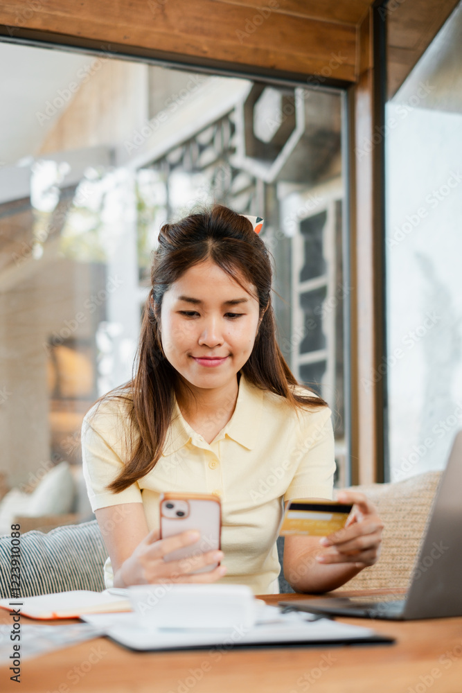 Smiling woman using smartphone and credit card for online shopping while sitting at home near a window. Smiling woman using smartphone and credit card for online shopping while sitting at home near a window.