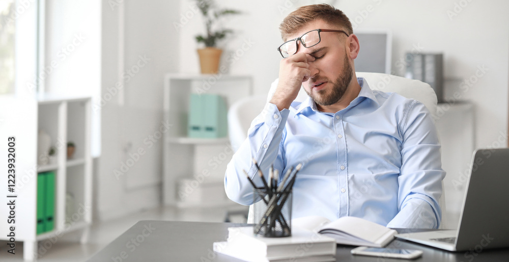 Young man suffering from headache in office Young man suffering from headache in office
