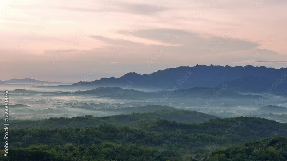 Aerial view of Natural scenery of green forest and hills on the horizon in slightly foggy morning. Sunrise over tropical rural landscape. Indonesia Aerial view of Natural scenery of green forest and hills on the horizon in slightly foggy morning. Sunrise over tropical rural landscape. Indonesia