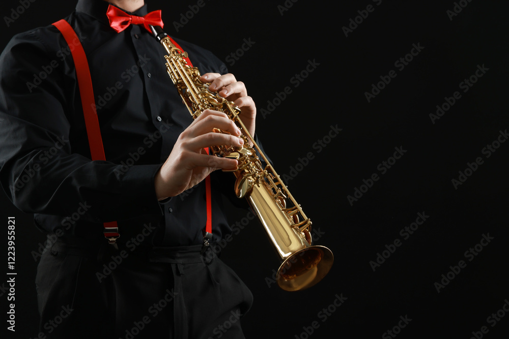 Obraz premium Professional musician playing soprano saxophone on black background, closeup. Space for text