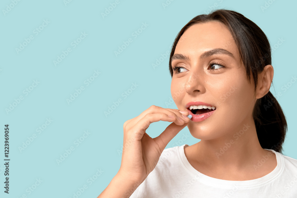 Pretty young woman taking pill on blue background, closeup Pretty young woman taking pill on blue background, closeup