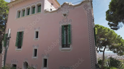 A pink building with decorative windows and greenery in Park Güell, Barcelona, Spain