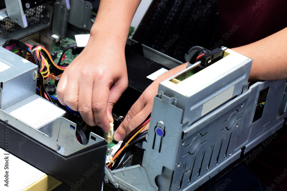 A computer technician is plugging the power cord into the computer motherboard. A computer technician is plugging the power cord into the computer motherboard.