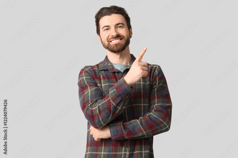Young man pointing up on light background