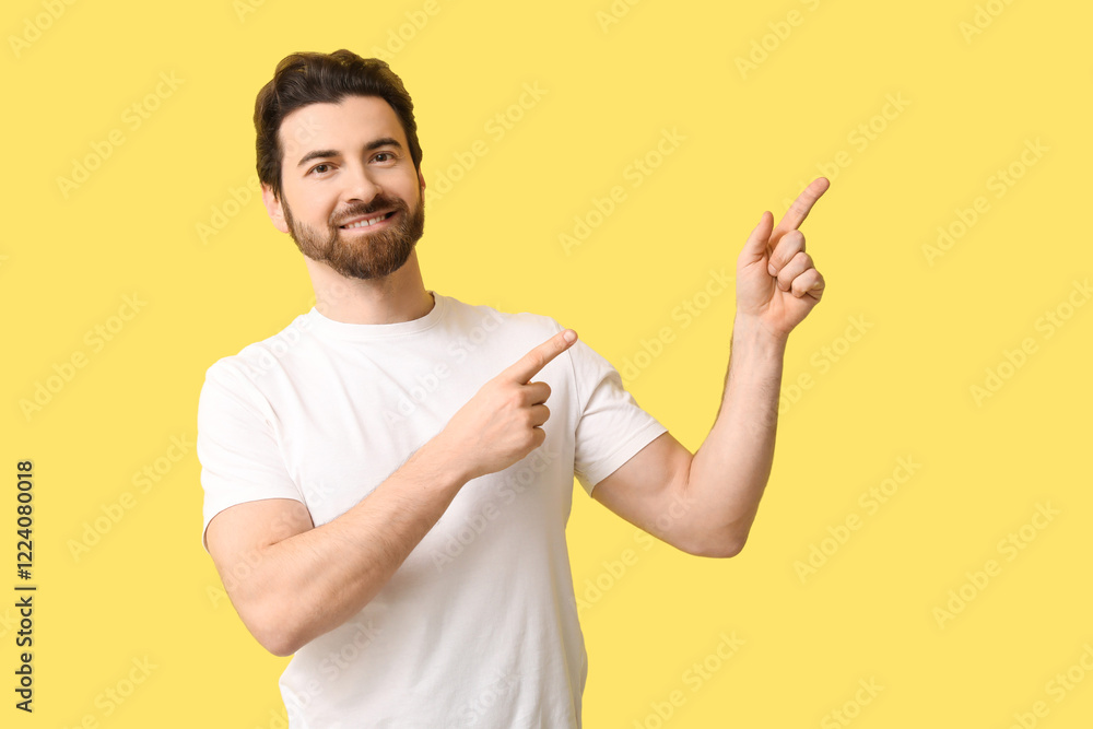 Young man pointing at something on yellow background Young man pointing at something on yellow background