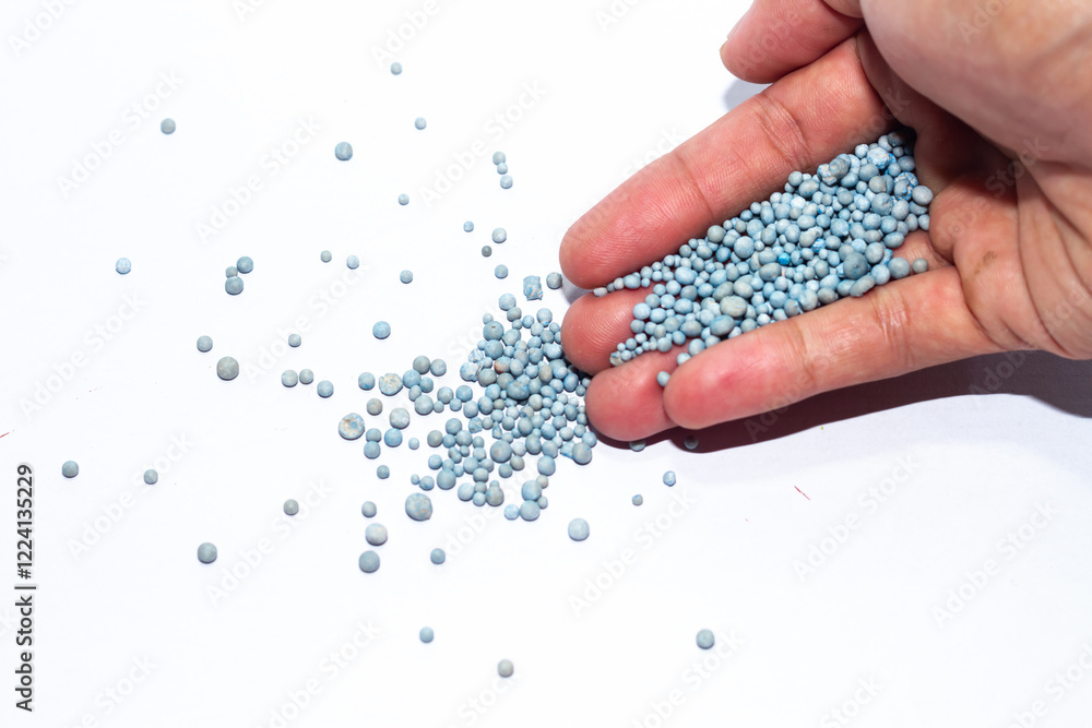 Photo of hand holding blue chemical fertilizer granules. Photo of hand holding blue chemical fertilizer granules.