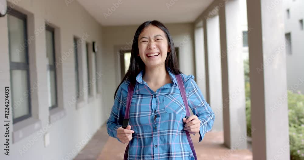 Teenage Asian girl with a joyful expression stands in a school corridor in high school Teenage Asian girl with a joyful expression stands in a school corridor in high school