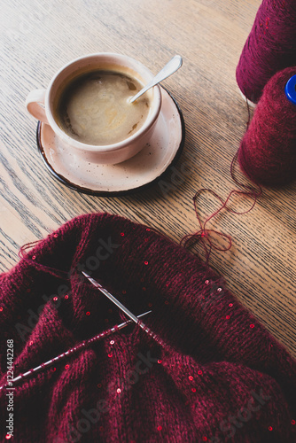 Obraz na płótnie Red knitted sweater with sequins and knitting needles with coffee cup on table. Sequin pattern in needlework with cappuccino. Knitting hobby. Knitted fashion concept. Sequins pattern in knitwear. w salonie