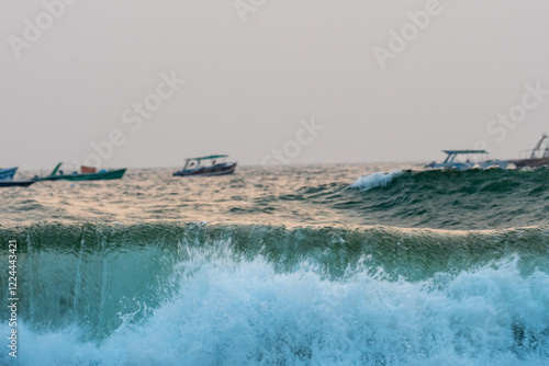 Closeup view of wave with boats in the background  photo