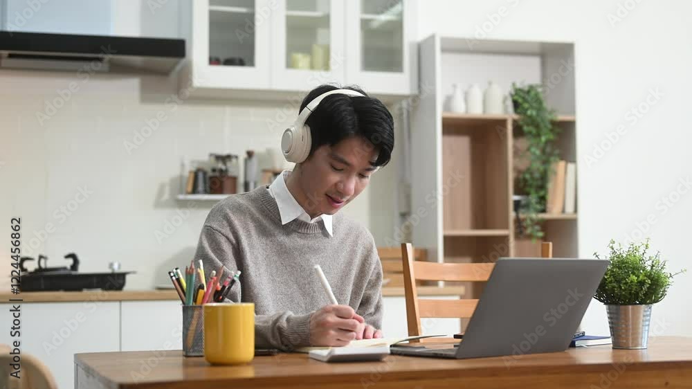 Attractive happy young Asian student studying at the college library, sitting at the desk Attractive happy young Asian student studying at the college library, sitting at the desk