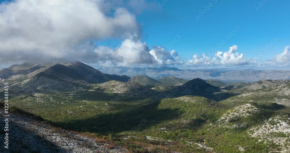 Aerial view of rugged mountains and lush natural surroundings near Dubrovnik, Croatia. Blue cloudy sky creates mountain shades Aerial view of rugged mountains and lush natural surroundings near Dubrovnik, Croatia. Blue cloudy sky creates mountain shades
