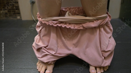 Woman lowering pajama pants to sit on toilet photo