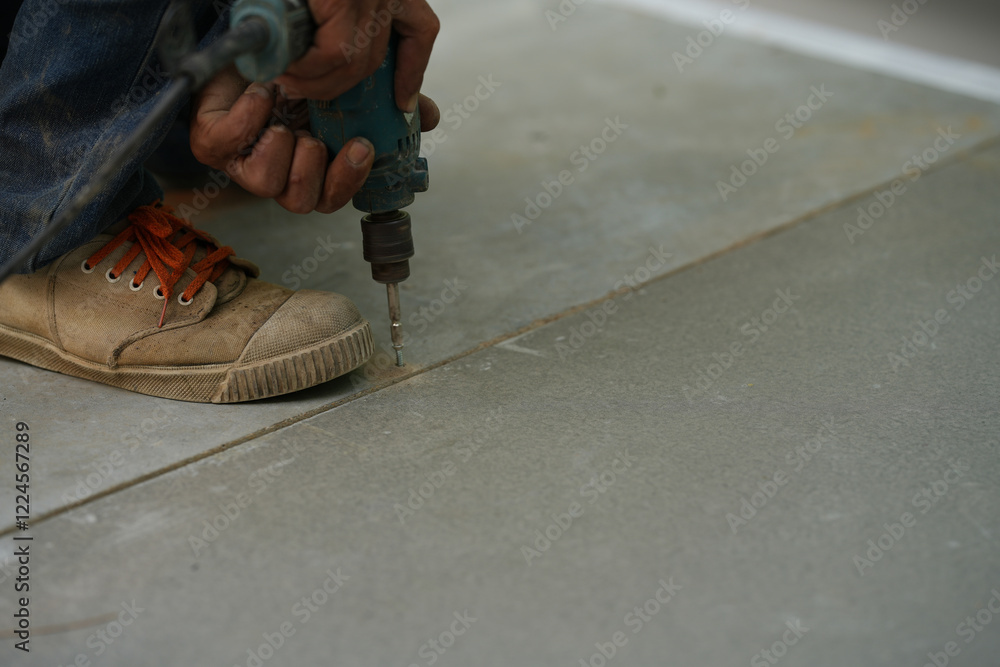 Close-up of power drill fastening screw to Cement slabs.