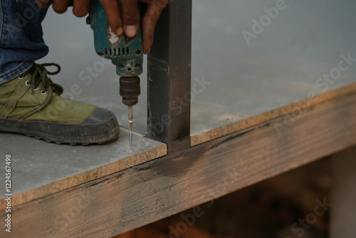Close-up of power drill fastening screw to Cement slabs.