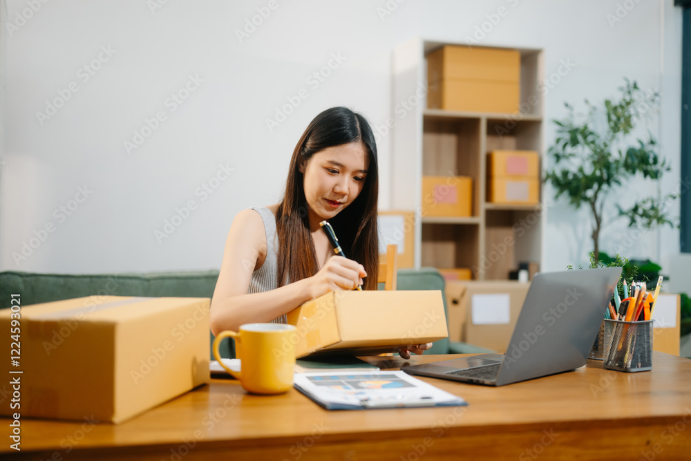 Young business owner woman prepare parcel box and standing check online orders for deliver Young business owner woman prepare parcel box and standing check online orders for deliver