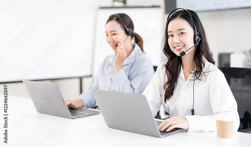 Young Asian Customer service representative using a headset while working at a call center Young Asian Customer service representative using a headset while working at a call center