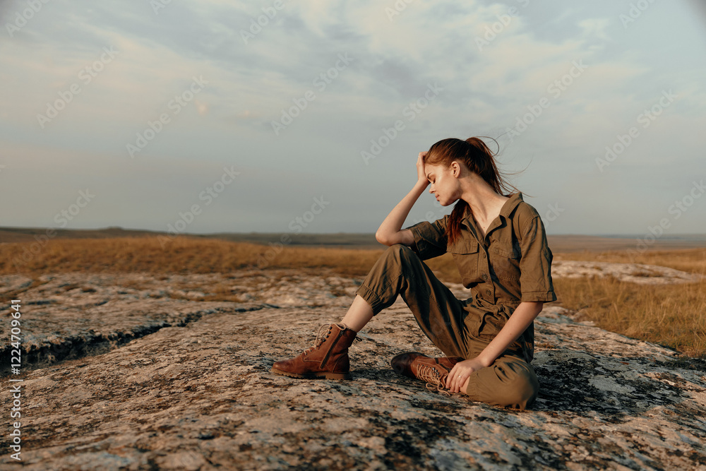 Lonely woman contemplating life on top of a rock in the middle of a field as a concept of solitude and peace Lonely woman contemplating life on top of a rock in the middle of a field as a concept of solitude and peace