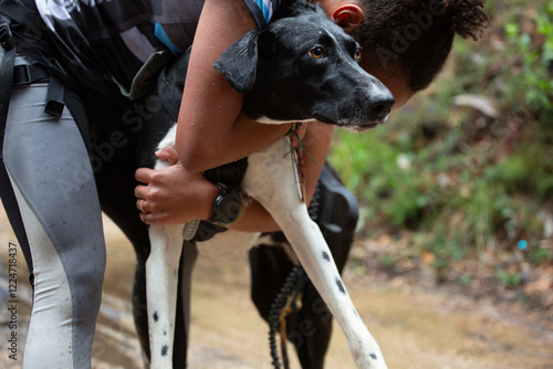 A mushing runner hugs her dog at the end of the race
