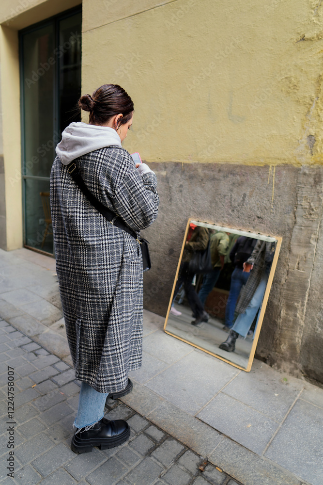 Woman using smartphone next to mirror at el rastro flea market in madrid