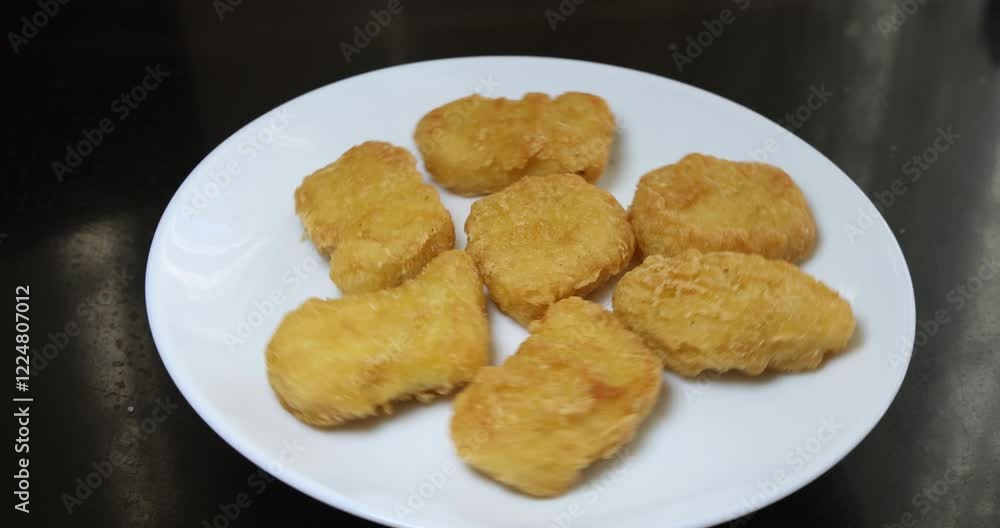 Chicken nuggets lie on a slowly rotating plate Chicken nuggets lie on a slowly rotating plate
