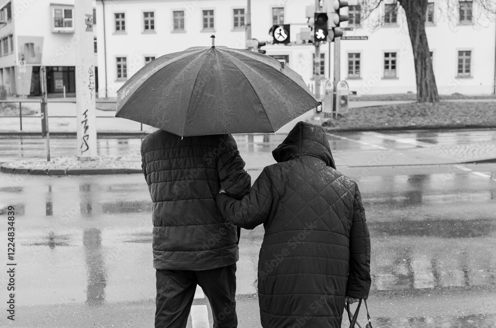 Pensioner couple walking in the rain at a traffic light in the city of black and white photography Street photography