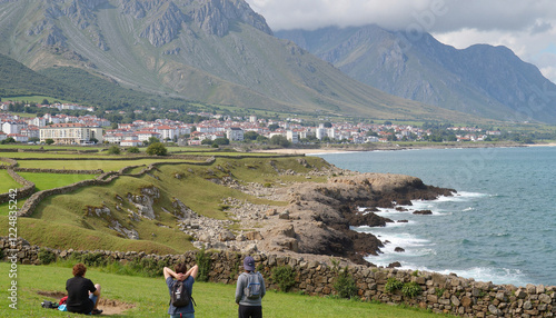 Travelers overlooking a scenic coastal view with mountains, experiencing homesickness during their journey