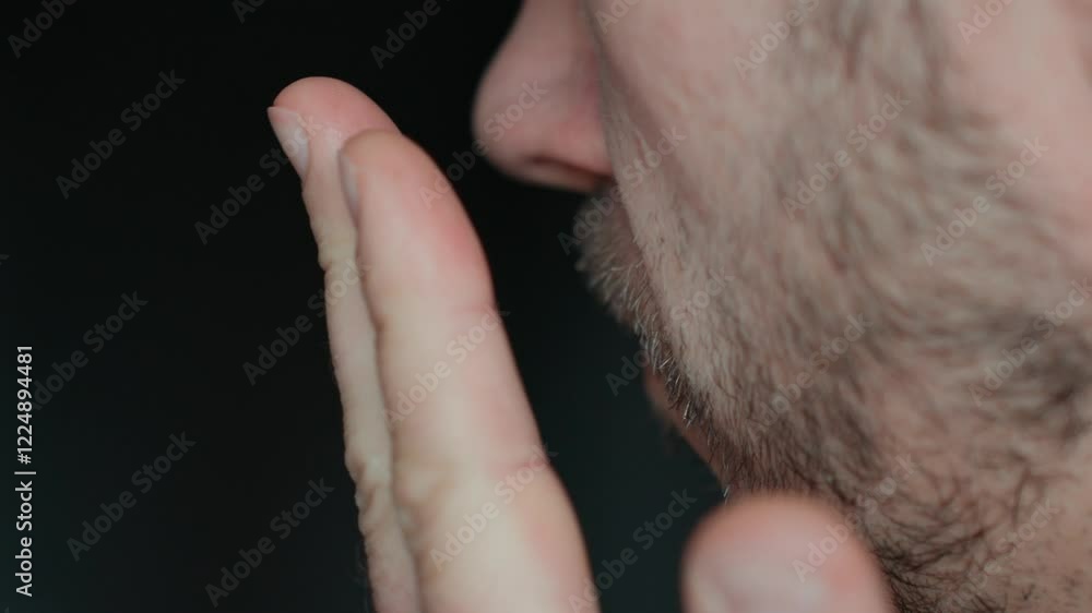 Bad breath from mouth. Close-up of man checking his breath by exhaling into his hand, showing concern about oral hygiene or bad breath Bad breath from mouth. Close-up of man checking his breath by exhaling into his hand, showing concern about oral hygiene or bad breath