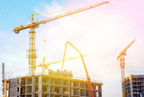 Builder workers during formworks and pouring concrete through a oncrete pump truck connected to a ready-mixed truck. Concrete line and boom pumping at construction site. Tower cranes working photo