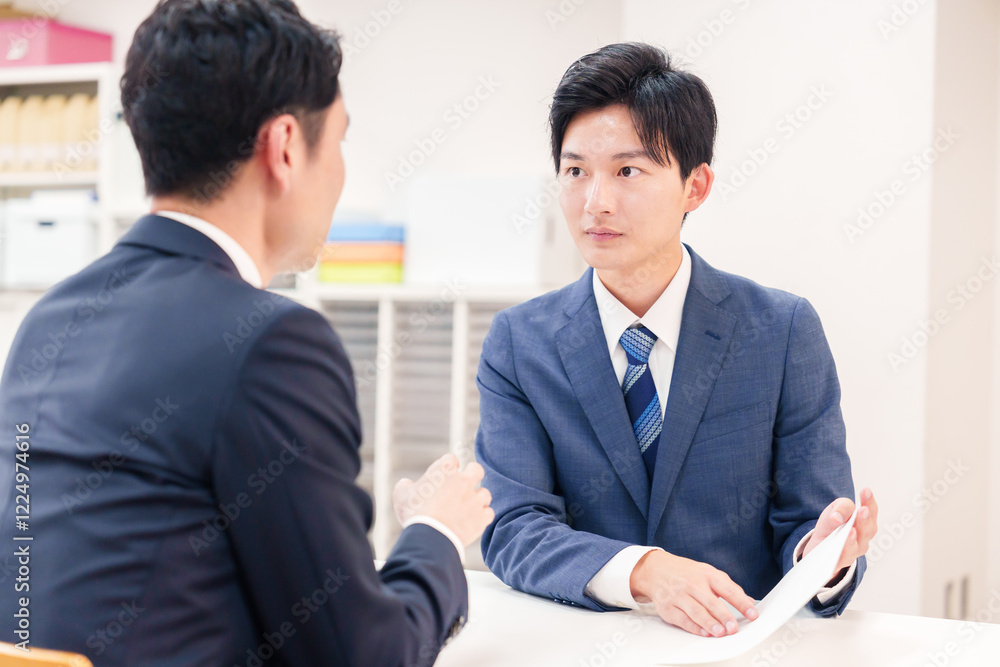 窓口で来客の対応をするビジネスマン