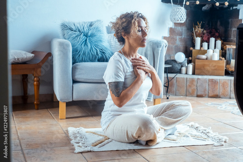 Bild auf Leinwand Woman meditating deeply in lotus position on the floor at home, practicing yoga