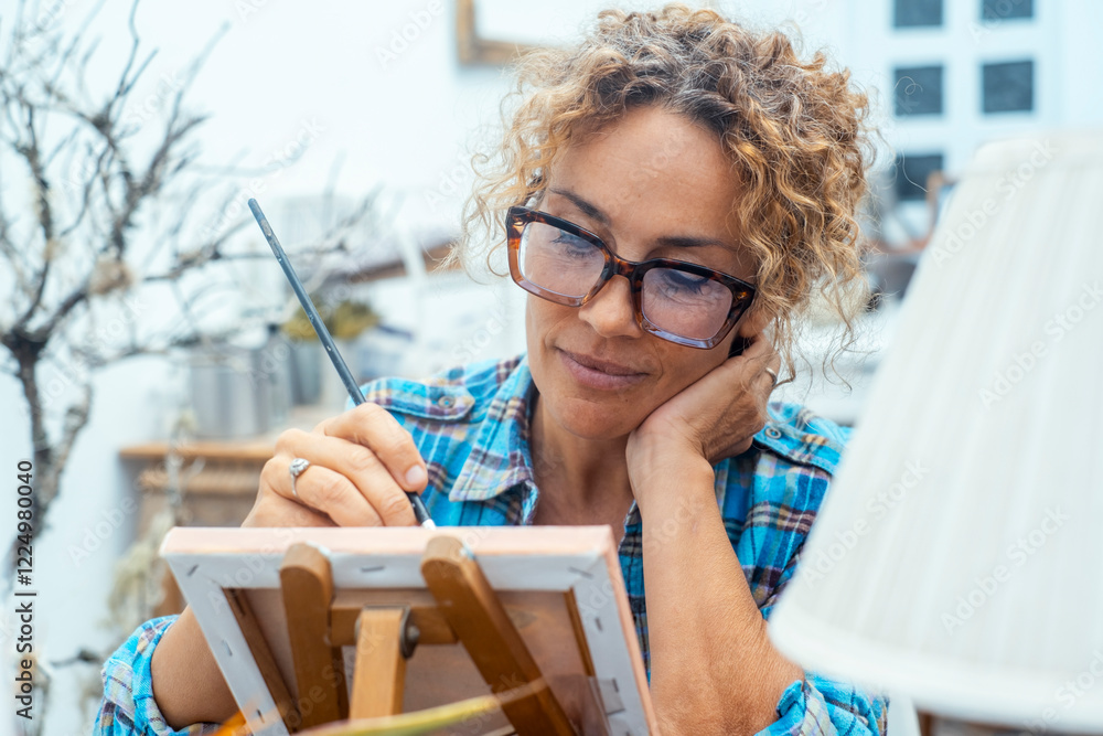© simona - A modern woman wearing glasses uses her free time to paint in her house, working on art restoration or a personal hobby, creating a relaxing environment focused on wellbeing and creativity © simona - A modern woman wearing glasses uses her free time to paint in her house, working on art restoration or a personal hobby, creating a relaxing environment focused on wellbeing and creativity