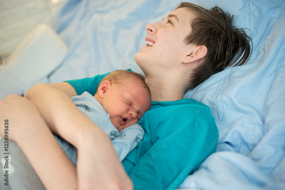 12 year old boy hugs his sleeping newborn brother. Happy teenager lies with his baby brother on the bed. 12 year old boy hugs his sleeping newborn brother. Happy teenager lies with his baby brother on the bed.