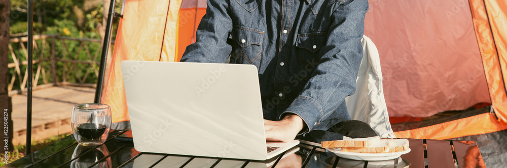 © doidam10 - Young business man working computer on peak hill. Hiker online shopping on laptop at sunset, sunrise on top mountain, freelance person remote work with digital tablet. travel vacation holiday concept