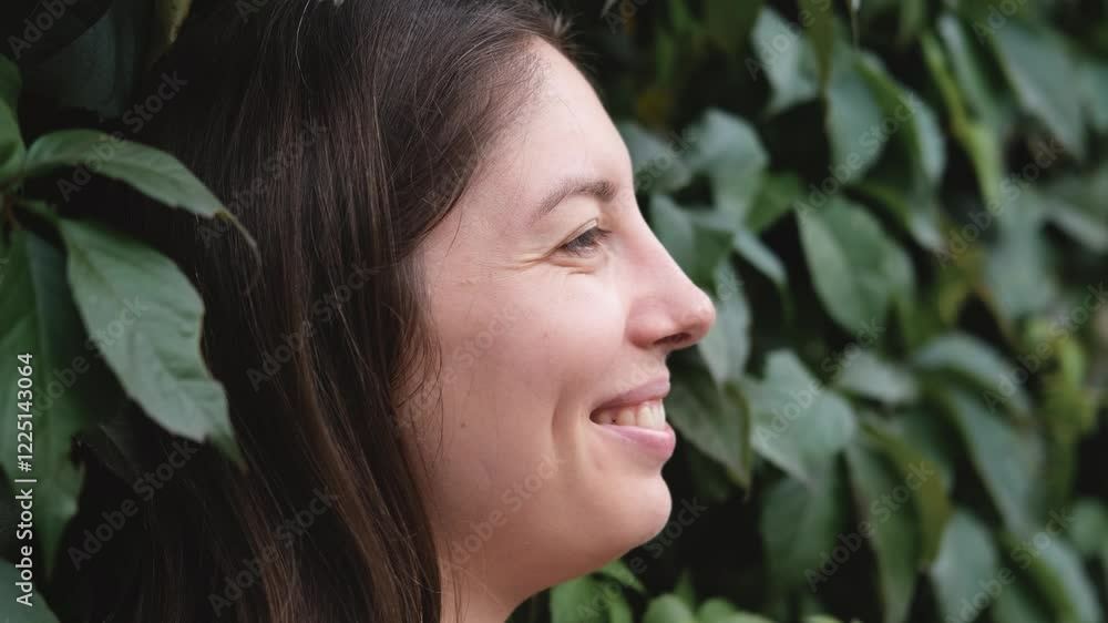 A cute young woman stands near a wall covered with green leaves. A cute young woman stands near a wall covered with green leaves.