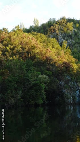 Wallpaper Mural Rocky steep mountains with an autumn forest are reflected in the water on a warm sunny evening. A small mountain lake in a gorge near the town of Uzice in Serbia. 4k vertical footage. Torontodigital.ca