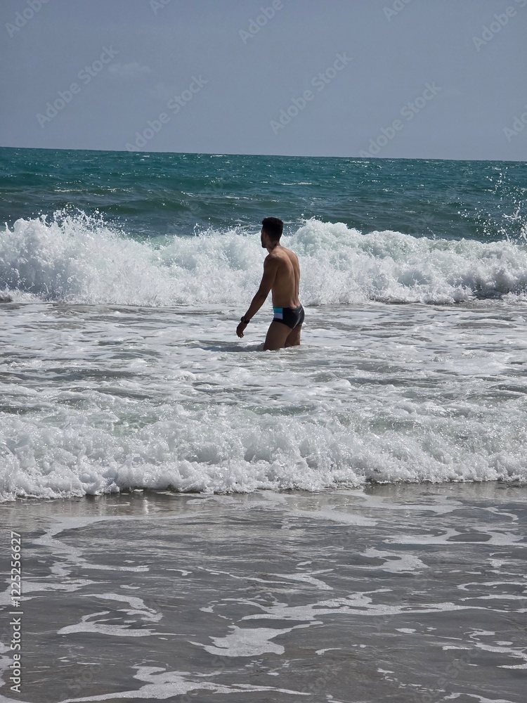 Young Man Enjoying Refreshing Ocean Waves at a Stunning Beach Young Man Enjoying Refreshing Ocean Waves at a Stunning Beach