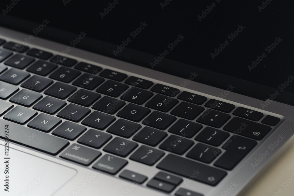 Angled close up of laptop keyboard and screen with light and dark shading Angled close up of laptop keyboard and screen with light and dark shading