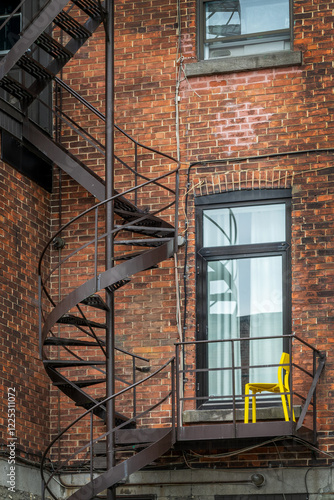Obraz na płótnie Rusty metallic outside spiral stairs on a brick building in Montreal, Canada w salonie