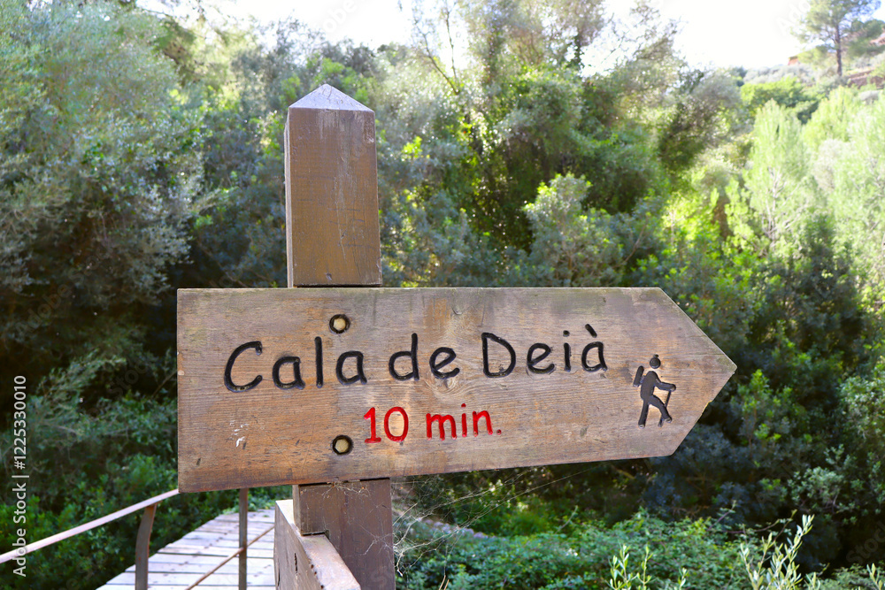 View of wooden street sign with direction of Deya Cove in village Deia, Balearic Islands, Spain