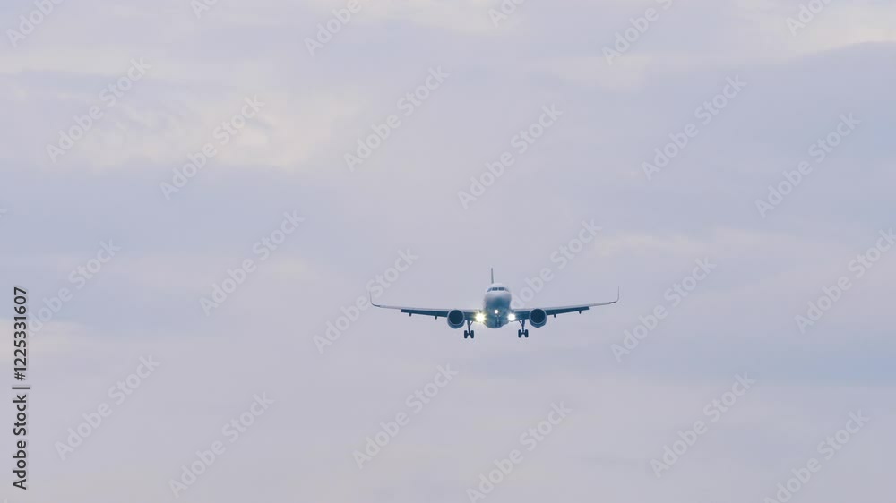 Jet airplane with unrecognizable livery approaching landing, long shot, front view. Travel concept Jet airplane with unrecognizable livery approaching landing, long shot, front view. Travel concept