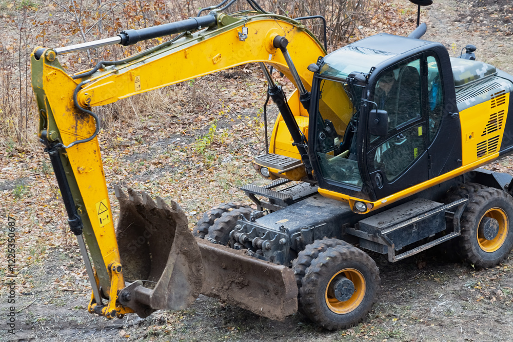 Close-up of a yellow backhoe excavator on an earth site in autumn, preparation for construction activities, excavator operation in construction. Close-up of a yellow backhoe excavator on an earth site in autumn, preparation for construction activities, excavator operation in construction.